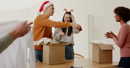 Volunteer raising shirt spurring diverse volunteers packing holiday packages with gift box at table