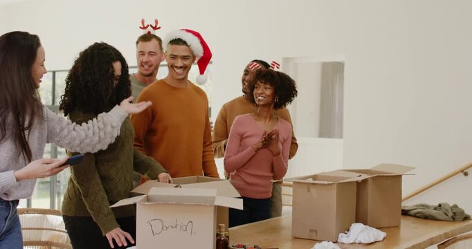 Six volunteers huddling after smartphone signal, pulling gift from donation box and smiling at home