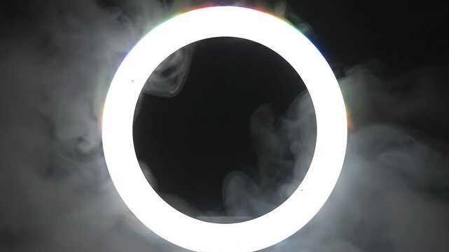 Dynamic radiant light ring with billowing smoke plumes forming an ethereal visual base effect on deep darkness