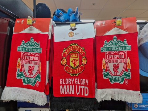 MANCHESTER, UK - JULY 19, 2025: Official Manchester United and Liverpool F.C. football scarves or muffler displayed for sale in a shop at Manchester Airport, highlighting the fierce rivalry.