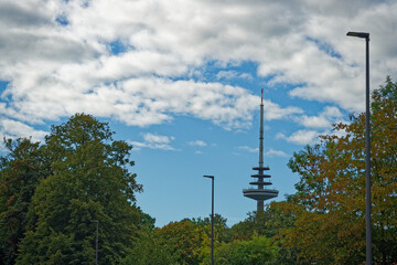 Obraz premium Kiel telecommunication tower rising above treetops under blue sky in Germany