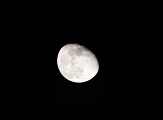 A high-resolution, astronomical shot of the Moon in its gibbous phase, captured against the deep black of the night sky.