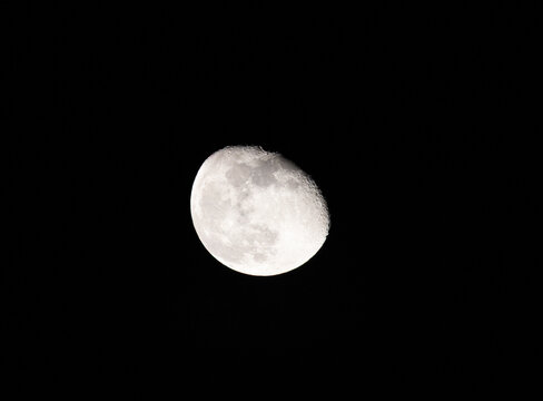 A high-resolution, astronomical shot of the Moon in its gibbous phase, captured against the deep black of the night sky. - Powered by Adobe