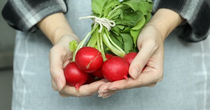 Woman with bunch of fresh radishes indoors, closeup