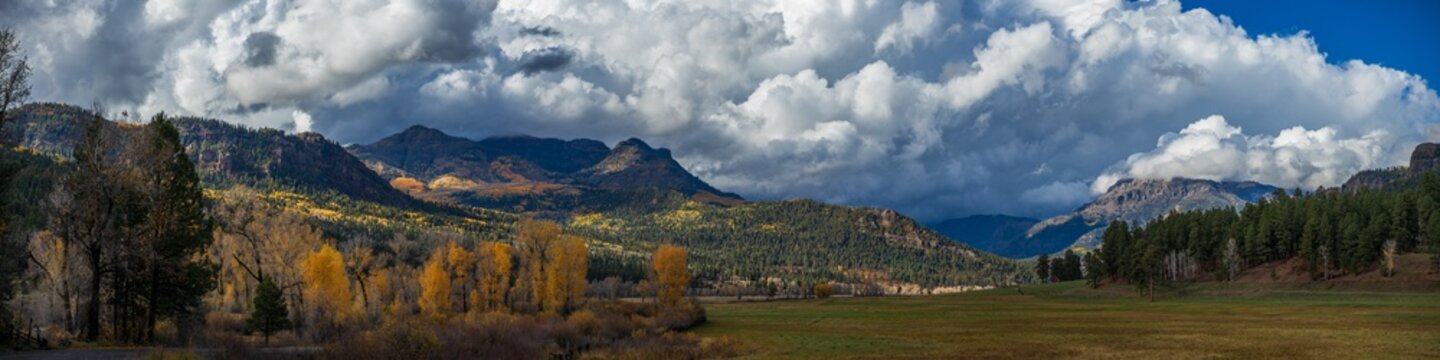 autumn meadow panorama with dramatic mountains and clouds
