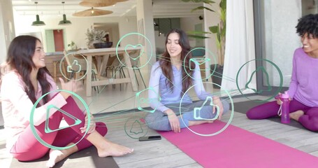 Center woman tapping smartphone on mat, causing social icons as friends sharing yoga - Powered by Adobe
