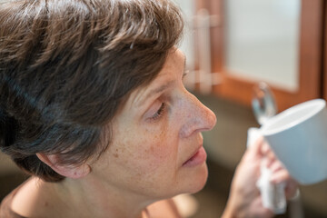 A tired woman pulls a coffee mug from the cabinet