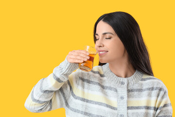 Fototapeta premium Beautiful woman drinking Turkish tea on yellow background
