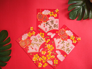 Chinese New Year Red Envelopes (Ang Pao) with Golden Calligraphy and Green Leaves on Red Background