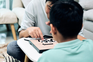 Father guiding child on Go board, pointing at strategic positions while discussing moves; logical thinking, family learning, and cognitive development