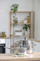 Stainless cooking pots on wooden table in kitchen