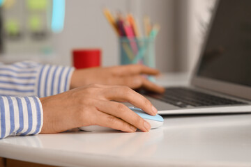 Hands of woman using computer mouse and laptop at table in office