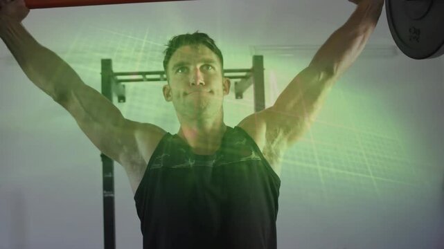 Male lifter gripping loaded barbell in gym, pressing overhead then hinging training shoulders, back