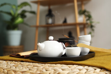 Asian tea set on rattan pouf in room, closeup