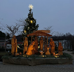 Wooden nativity scene in the night light in the city. Christmas Advent time. Christmas tree with candles and christmas lights. Prague.