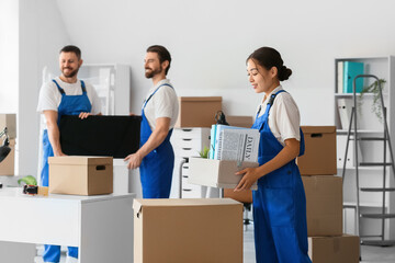Female Asian loader carrying box in office on moving day