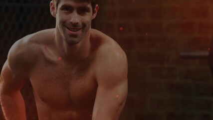 Male gym athlete adjusting shorts, rising and reaching kettlebell, preparing lift, embers around