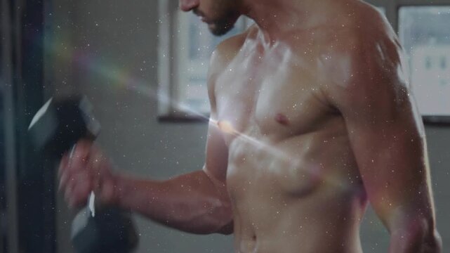 Male fitness model performing hex dumbbell curls camera sharpening lens flares showcasing torso