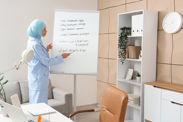 Young Muslim businesswoman learning Arabic language near flipchart in office