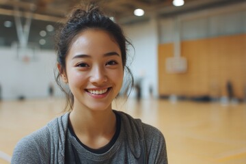 Happy young female chinese sports college student talking directly to camera in a sports hall. 