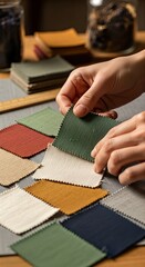Hands selecting fabric swatches for textile design and color palette creation.
