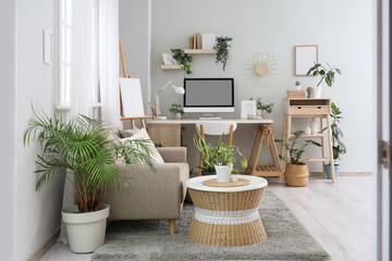 Interior of light office with workplace, sofa and green plants