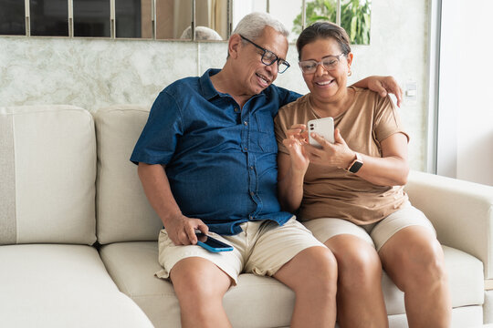 Senior couple sharing smartphone happy moment at home - Powered by Adobe
