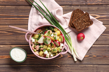 Composition with bowl of tasty okroshka, sour cream, bread and green onion on wooden background