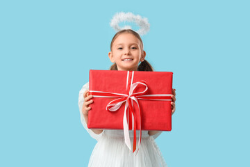 Naklejka premium Cute little girl dressed as Cupid with gift box on blue background. Valentine's Day celebration