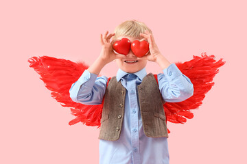 Naklejka premium Cute little happy boy in cupid wings with hearts on pink background. Valentine's Day celebration