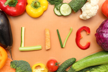 Composition with word LIVE and different fresh vegetables on color background, closeup