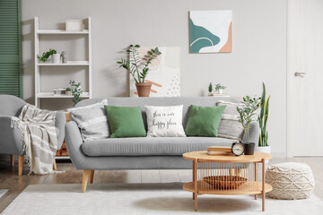 Interior of light living room with sofa, shelf unit and plants