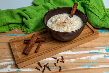 Hominy (canjica or mungunz&aacute;). Yellow corn with cinnamon in a ceramic bowl. Selective focus. Typical brazilian dessert of june festival in winter - Concept image.