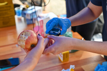 Nurse pricking a patient's finger to perform a blood glucose test.