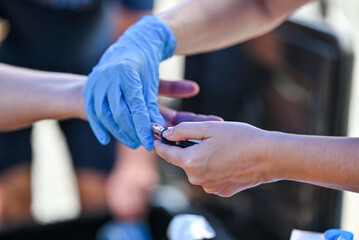 Nurse pricking a patient's finger to perform a blood glucose test.