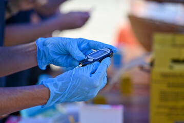 Nurse pricking a patient's finger to perform a blood glucose test.