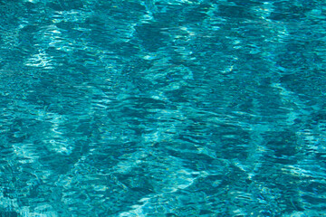 Fototapeta premium Water background. Blue water, ripples and highlights. Texture of water surface and tiled bottom.