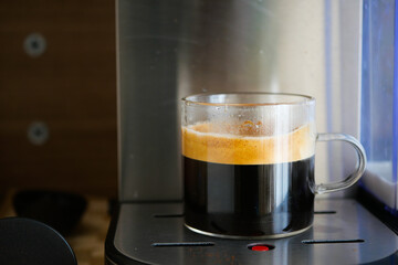 Coffee brewing in clear cup on countertop in kitchen