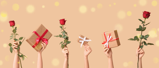 Female hands with gift boxes and red rose flowers on beige background. Valentine's Day celebration