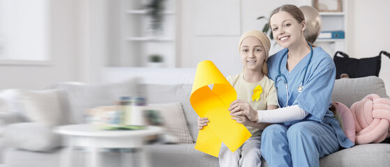 Little girl after chemotherapy with yellow ribbon and nurse sitting on sofa at hospital. Childhood cancer awareness concept