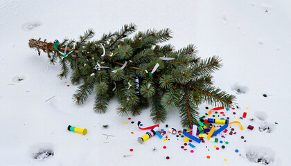 A discarded Christmas tree with remnants of confetti and ribbons on snow