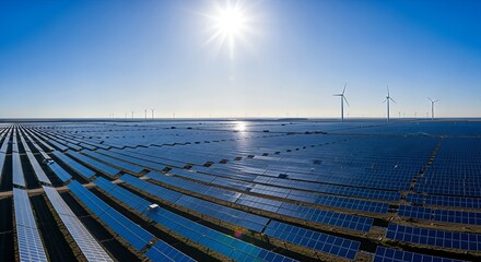 Vast solar panel field under bright sun with wind turbines in the distance.