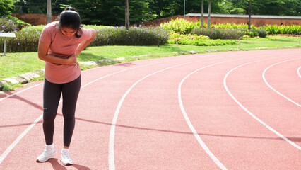 Asian women holding her stomach with painful expression while outdoors, indicating abdominal pain...