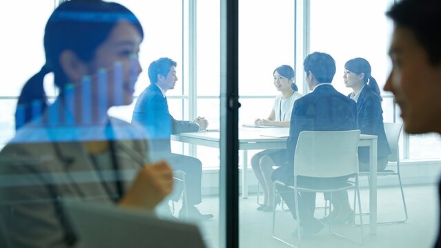 ガラス越しに見る会議室で打ち合わせをするビジネスチーム