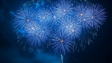 Vibrant blue fireworks exploding in night sky with bright sparks and colorful lights