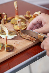 Left-handed cuts raw mushrooms with sharp knife