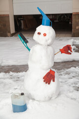 Funny car snowman stands in front of  garage