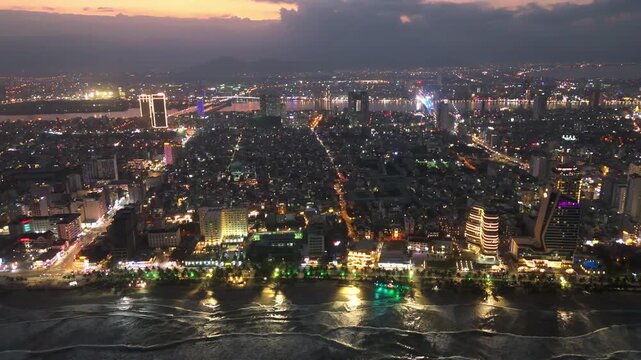 Da Nang, Vietnam Aerial drone sunset cityscape skyline of the city illuminated at night with bridge crossing the river traffic road and skyline modern skyscraper 