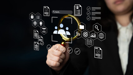 Business professional uses a magnifying glass to analyze digital data with various icons, highlighting importance of data management and information security in modern workplaces. Gantry