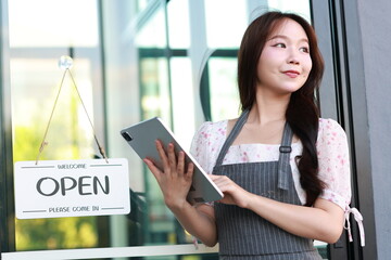 Female owner of coffee shop or restaurant turning round sign to open. Smiling young asian woman owner, employee retail coffee shop woman hand in setting sign board to open for welcome customer, reopen